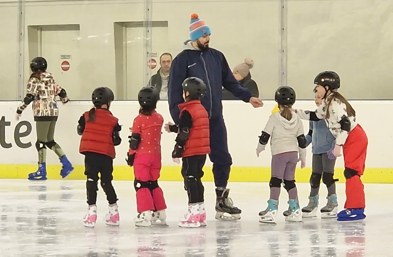 Antrenor, copii cu căști pe gheața patinoarului, programul Crestem campioni